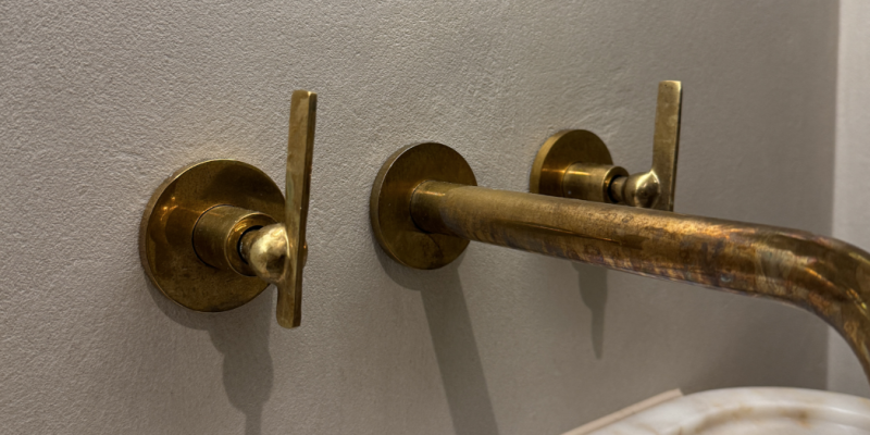 Microcement wall finish behind brass taps. 