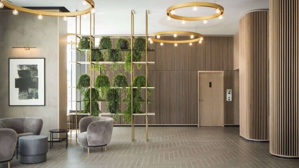 Viero UK Marmorin Hydro applied to columns complementing wooden paneled walls, grey seating area, and green plants in modern interior.