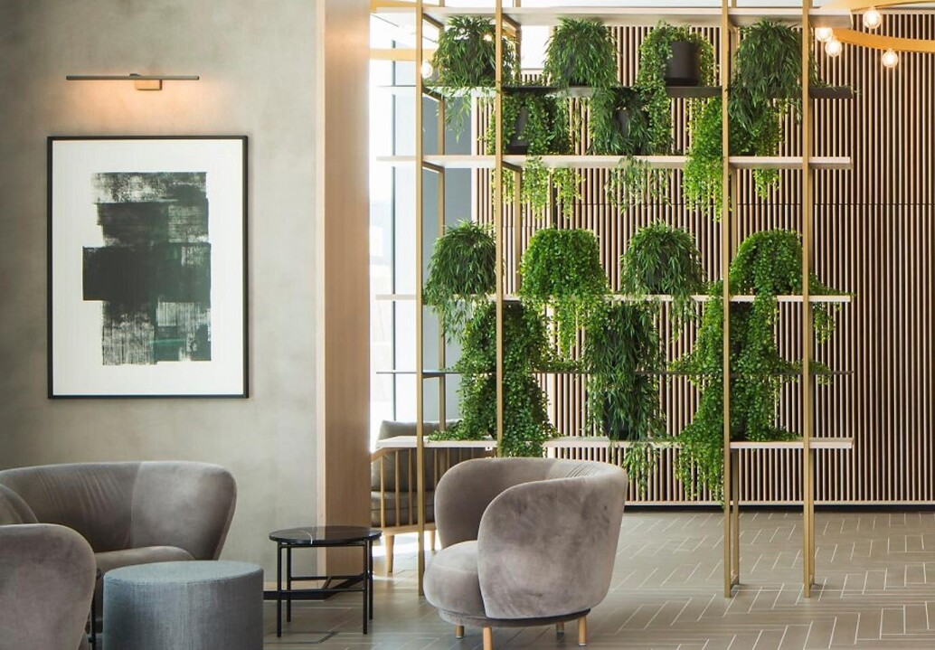 Close up image of Viero UK Marmorin Hydro applied to columns complementing wooden paneled walls, grey seating area, and green plants in modern interio